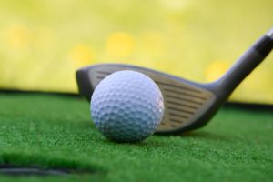 A Close-up view of Golf club and ball in grass.