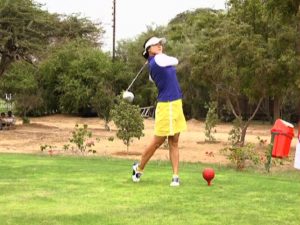 Female Golfer taking a shot in a golf ground.