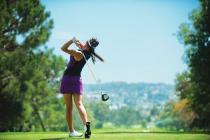 Female Golfer taking a shot in the golf course.