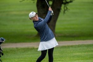 Woman taking a beautiful hit shot from a golf course.