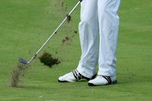 Image represents a professional golfer taking a hit shot from the ground.